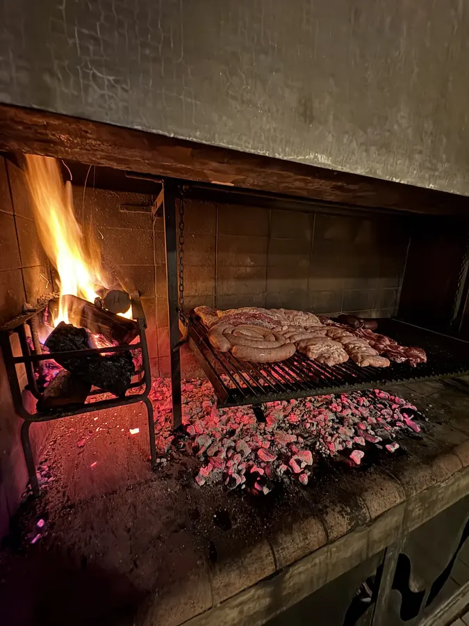 Parrilla con leña encendida y cortes cocinándose